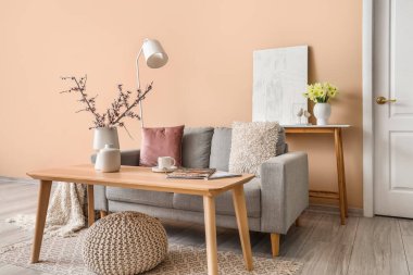 Gri kanepesi, masası ve lambası olan oturma odasının içinde.