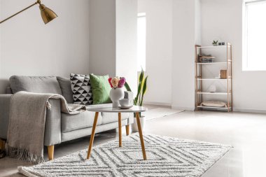 Masada gri kanepe ve çiçek açan sümbül çiçekleriyle aydınlık oturma odasının içinde.