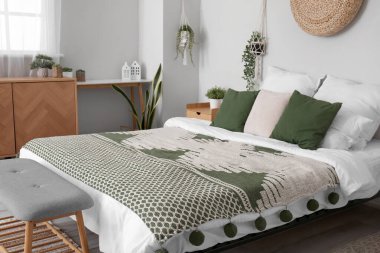 Konforlu yatak odası, ahşap dolap ve sallanan ev bitkileri.