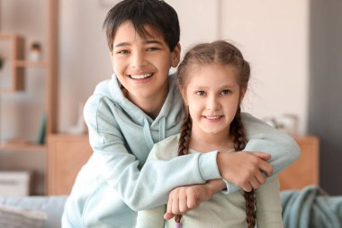 Küçük çocuk evde kız kardeşine sarılıyor.