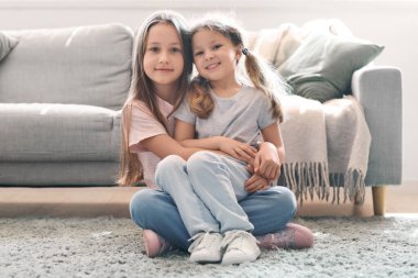 Evde kucaklaşan şirin küçük kız kardeşler.