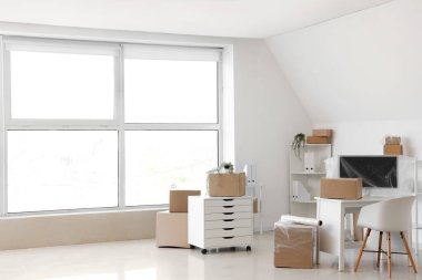 Karton kutularla aydınlık ofisin içi ve taşınma gününde gerilmiş film.