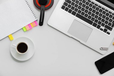 Kablosuz şarj pedi olan dizüstü bilgisayar, telefon ve beyaz arka planda bir fincan kahve.