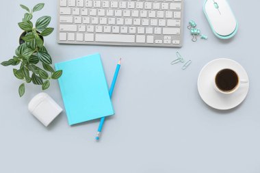 Gri arka planda bir fincan kahve, kırtasiye ve kulaklık olan klavye