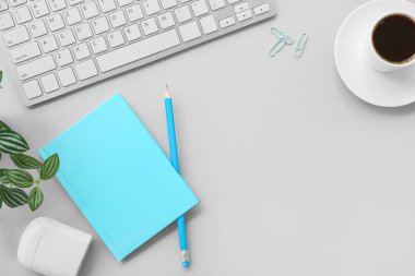 Gri arka planda bir fincan kahve, kırtasiye ve kulaklık olan klavye