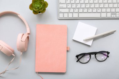 Gri arka planda kulaklık ve gözlüklü klavye