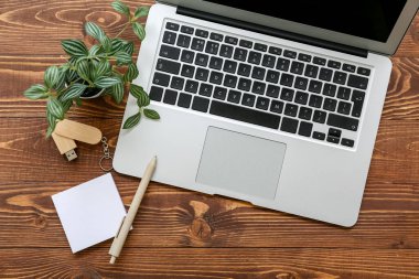 USB flaş sürücülü dizüstü bilgisayar ve kahverengi ahşap arka planda kırtasiye