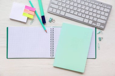 Beyaz ahşap zemin üzerinde farklı kırtasiye malzemesi olan klavye