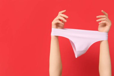 Kırmızı arka planda donu olan kadın elleri, yakın plan.