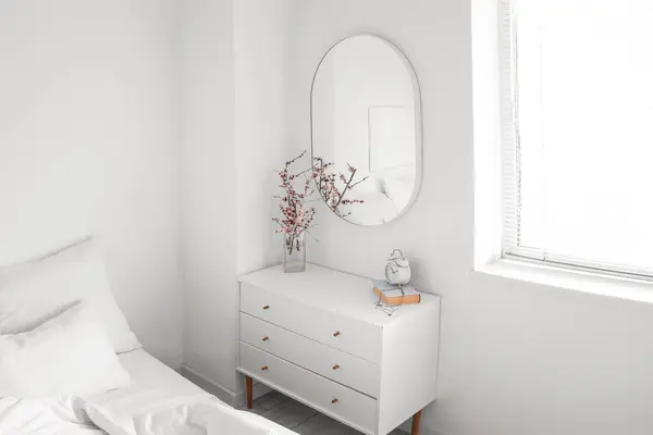 Interior of light bedroom with mirror and commode