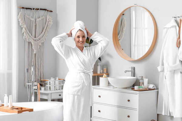 Зрелая женщина с полотенцем в ванной комнате