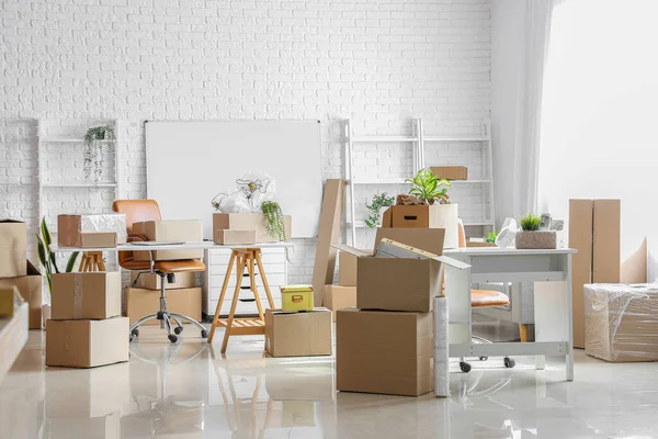 Workplaces with cardboard boxes in office on moving day