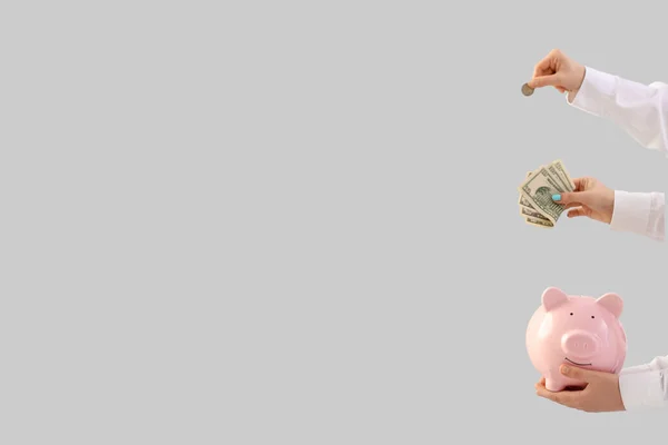 光の背景にお金と豚バンクを持つ女性 — ストック写真