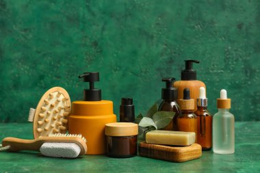 Renk arkaplanında masaj fırçası olan farklı kozmetik ürünleri.