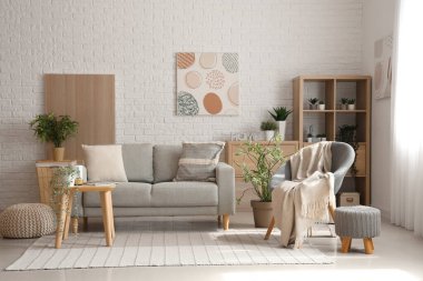 Işıl ışıl oturma odasının içinde rahat gri kanepe, koltuk ve kahve masası.