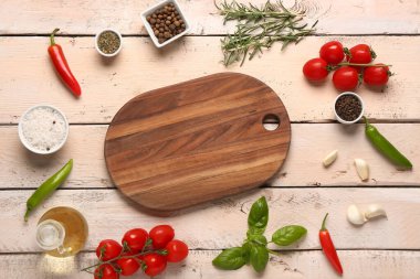 Açık ahşap arka planda kesim tahtası, baharat ve sebzelerle kompozisyon
