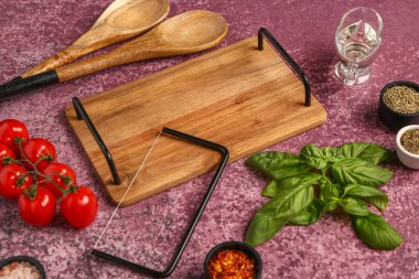 Ahşap mutfak tahtası, kaşıklar, baharatlar ve domateslerle renklendirilmiş.