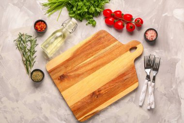 Ahşap kesim tahtası, taze baharatlar ve açık arkaplanda domatesler.