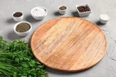 Ahşap mutfak tahtası, maydanoz ve arkaplanda farklı baharatlar.