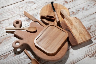 Açık ahşap arka planda kaşık ve bıçaklarla farklı kesme tahtaları.