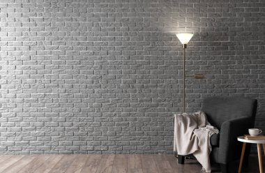 Parlayan lamba ve gri tuğla duvarın yanındaki rahat koltuk