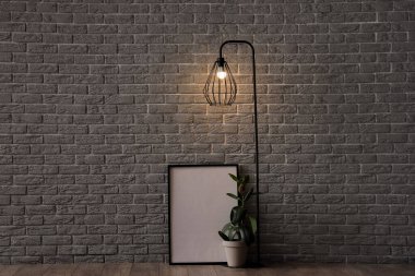 Parlayan lamba, çiçek ve gri tuğla duvarın yanındaki boş çerçeve.