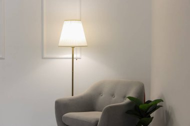 Parlayan lamba, gri koltuk ve beyaz duvarın yanındaki çiçek.