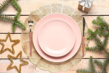 Köknar dalları, hediye kutusu ve bej ahşap arka planda çatal bıçaklı şenlik masası.