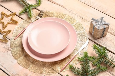 Köknar dalları, hediye kutusu ve bej ahşap arka planda çatal bıçaklı şenlik masası.