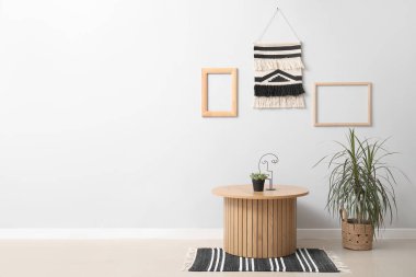 Ahşap sehpa ve makromlu gri duvarın yanındaki ev bitkisi.