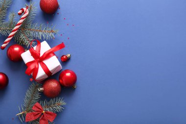 Topları ve mavi arka planda hediye kutusu olan Noel ağacı dalları