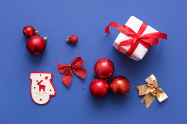 Mavi arka planda Noel baloları, fiyonklar ve hediye kutusu