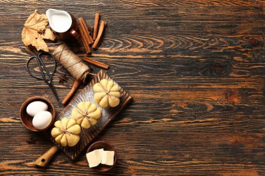 Balkabağı şekilli çörekler ve ahşap arka planda malzemeler