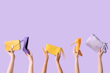 Farklı tarz çantalar tutan kadın eller ve leylak arka planda yüksek topuklar.