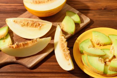 Tahta masanın üzerinde tatlı kavun parçaları olan tabak ve yemek.