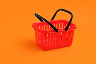 Turuncu arka planda küçük kırmızı alışveriş sepeti