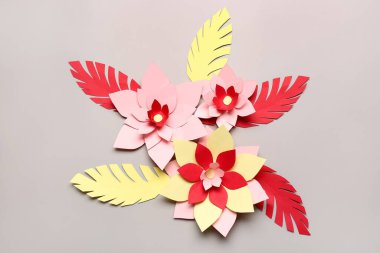 Gri arkaplanda yaprakları olan renkli origami çiçekleri