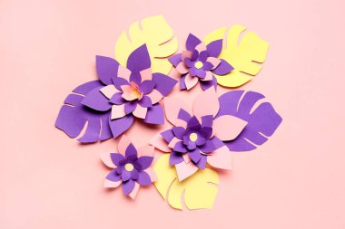 Pembe arka planda yaprakları olan renkli origami çiçekleri