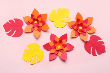 Pembe arka planda yaprakları olan renkli origami çiçekleri