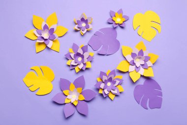 Renkli origami çiçekleri ve mor arkaplanda yapraklar