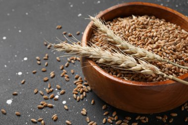 Tahta kasede tahıllar ve grunge siyah arka planda buğday kulakları.