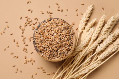 Tahta kase ve kahverengi arka planda buğday kulakları.