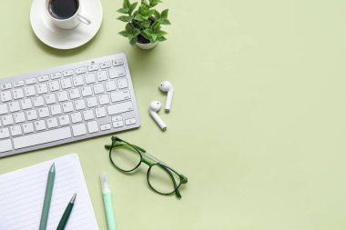 Klavye, bir fincan kahve ve açık yeşil arka planda kırtasiye malzemesi.