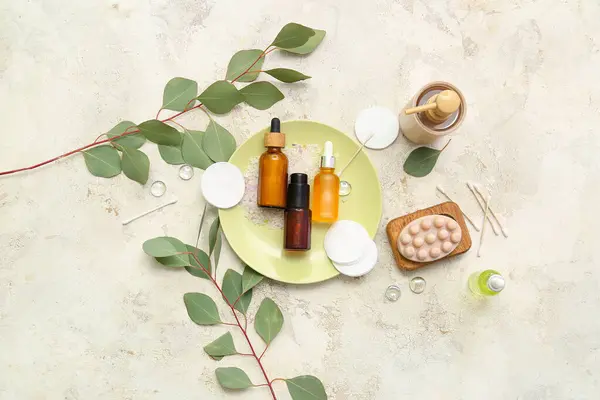 Composition with cosmetic products and eucalyptus branches on light background