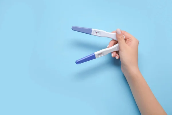 Female hand with pregnancy tests on color background