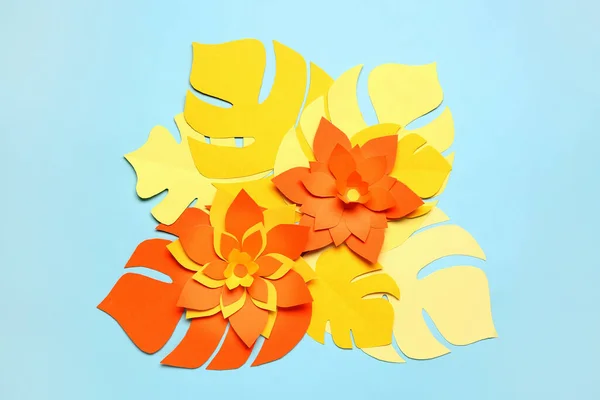 Colorful origami flowers with leaves on light blue background