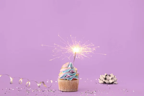 スパークラーと紫色の背景に装飾されたおいしい誕生日カップケーキ — ストック写真