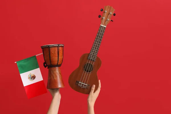 Mãos Femininas Segurando Bandeira Mexicana Ukulele Tambor Fundo Vermelho — Fotografia de Stock