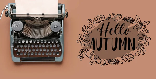 Vintage typewriter with text HELLO AUTUMN on brown background