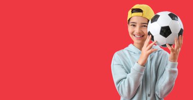 Kırmızı arka planda futbol topunu tutan küçük çocuk mesaj için yer açtı.